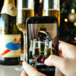 presa-una-foto-di-un-albero-di-natale-e-dei-vetri-del-champagne-con-uno-smartphone-63363316